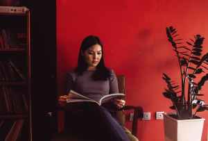 woman reading beside red painted wall